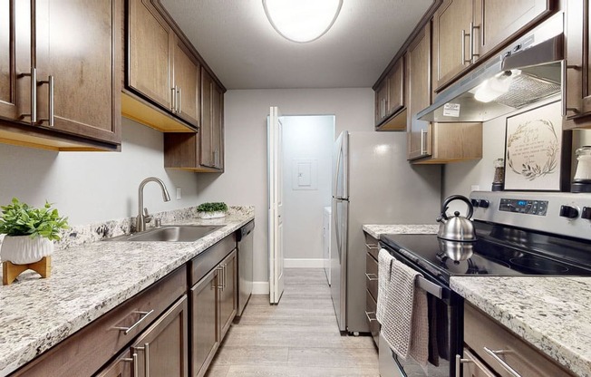 A kitchen with brown cabinets and a marble countertop.