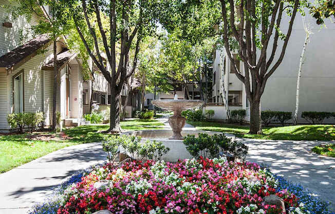 A garden with a variety of flowers in the foreground and a row of houses in the background at The Woods Apartments, California