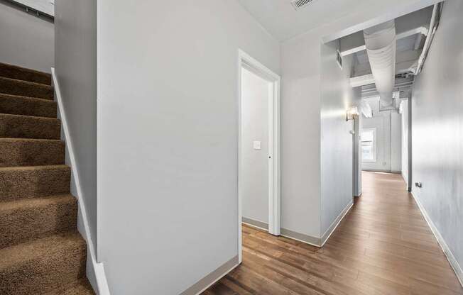 A hallway with a staircase on the left and a door on the right.