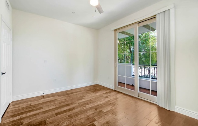 an empty living room with a sliding glass door to a balcony