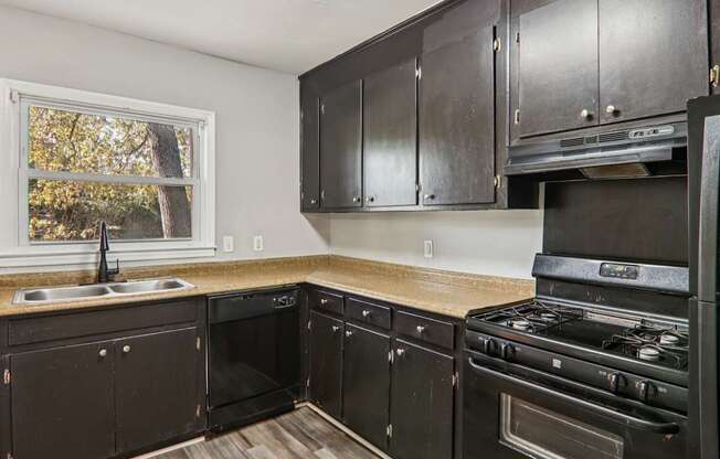 A kitchen with black cabinets and a stove top oven.