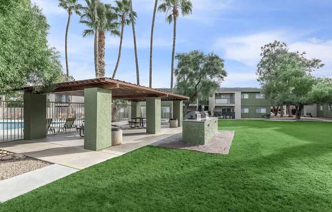 A sunny day at the poolside with palm trees and a covered seating area.