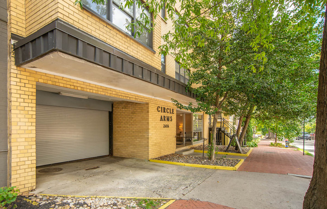 a building with a garage door and trees in front of it