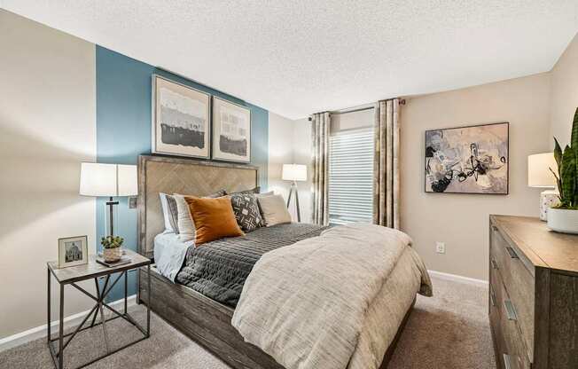 A bedroom with a bed, nightstand, and a painting on the wall.