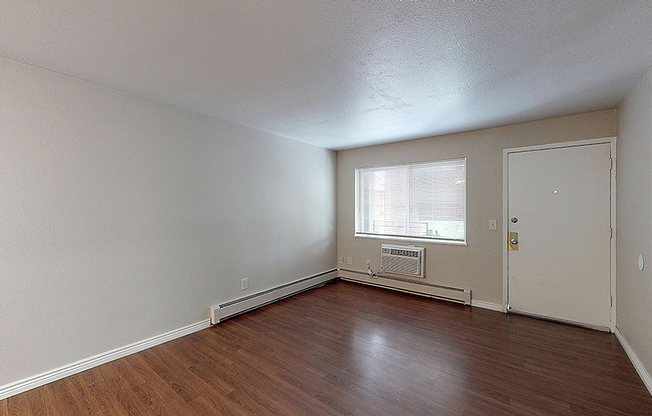 Bright and welcoming living space with sleek hardwood floors, neutral walls, and ample natural light from large windows.
