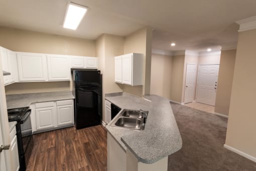 a kitchen with an island and a black refrigerator and a sink