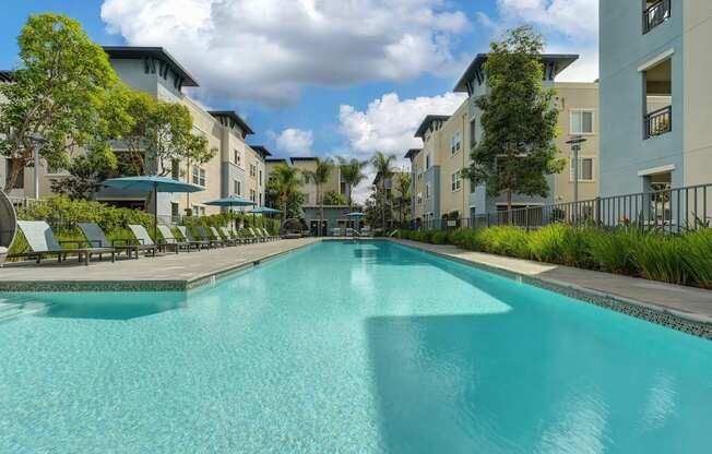 A large swimming pool in front of apartment buildings.