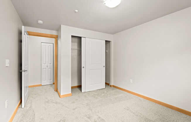 A room with a carpeted floor and three doors.