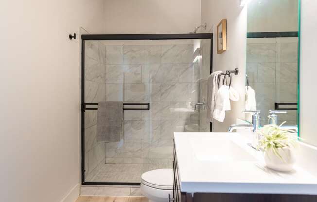 a bathroom with a white sink and toilet next to a shower with a glass door at The 22 Apartments, St. Louis Missouri