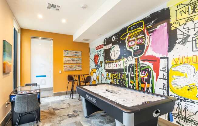 a game room with a pool table and graffiti on the wall