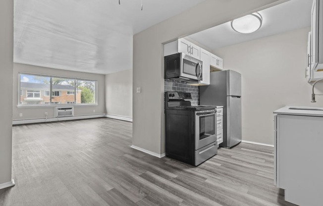 an empty kitchen with stainless steel appliances and a window