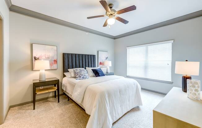 Furnished master bedroom with ceiling fan and large window for natural light at Avenues at Craig Ranch apartments for rent
