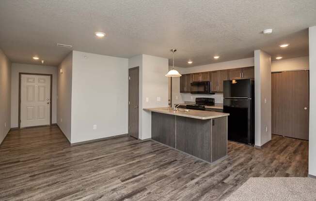 A kitchen with a black refrigerator and microwave, and a white countertop.