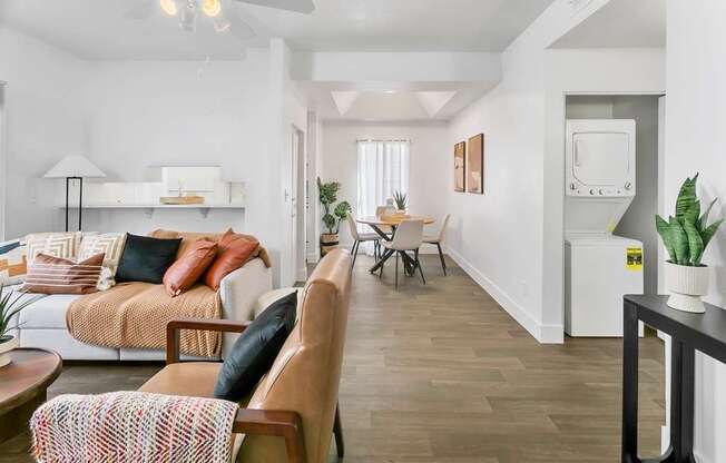 A living room with a couch, a chair, a table, and a potted plant.