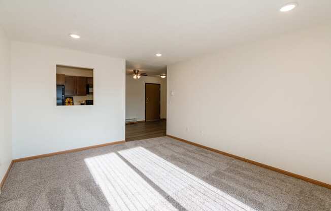 a living room with white walls and a carpeted floor. Fargo, ND Eagle Run Apartments
