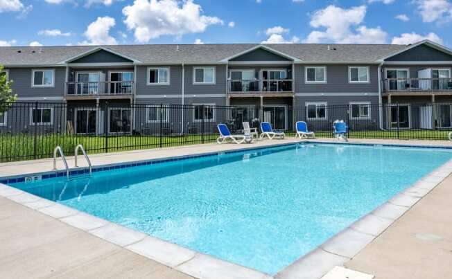 A large swimming pool in front of apartment buildings.