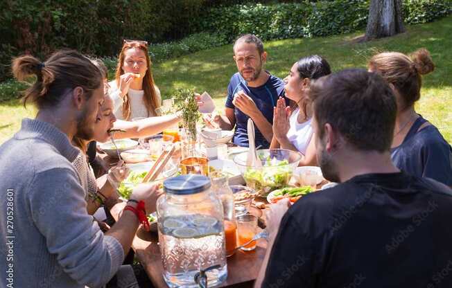 A group of people are gathered around a table eating and drinking.