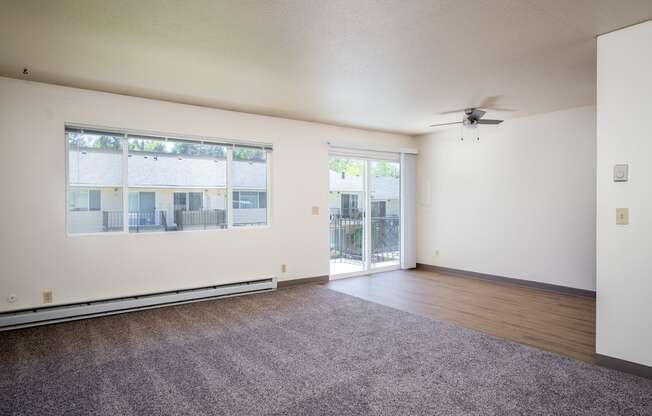 an empty living room with a ceiling fan and a window