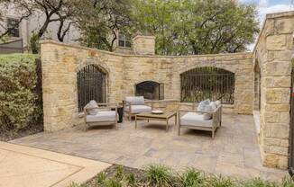 A patio with a stone wall and a fireplace.