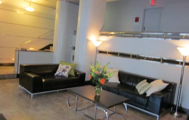 A black couch with a yellow pillow is in front of a white wall.