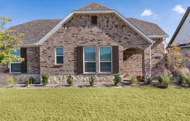 A charming cottage at Amavi Celina featuring brick detailing, a private front entry, and a landscaped yard that adds curb appeal.