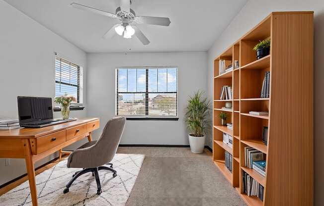 A room with a desk, chair, and bookshelf.