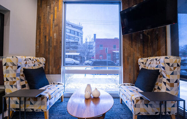 a living room with two chairs a table and a window
