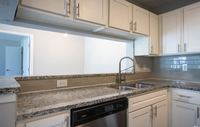 a kitchen with white cabinets and granite counter tops and a sink