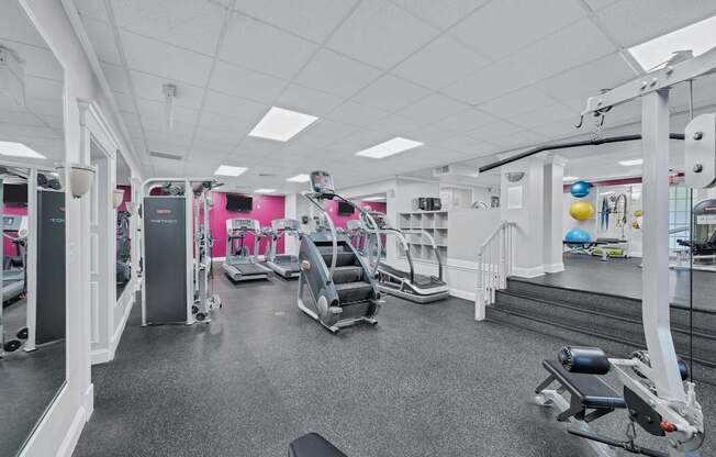 A gym with a variety of equipment including treadmills, weights, and exercise machines.