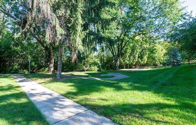 a park with trees and grass and a sidewalk