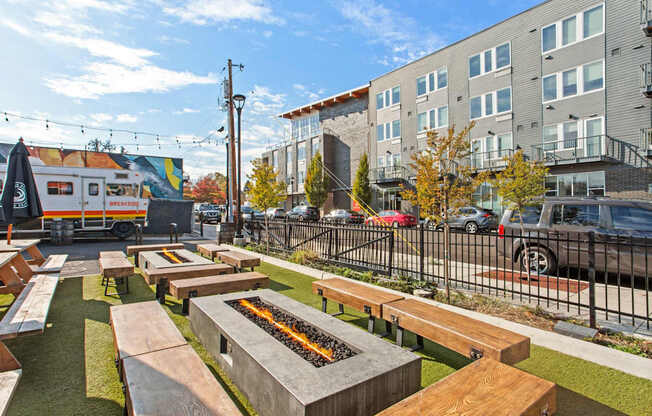A sunny day at an outdoor seating area with wooden benches and a food truck in the background.