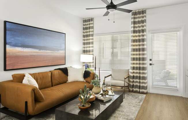 a living room with a brown couch and a ceiling fan