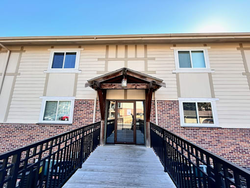 the front entrance of a building with stairs and a brick wall