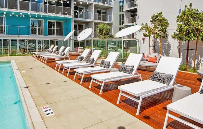 A pool with sun loungers and a building in the background.