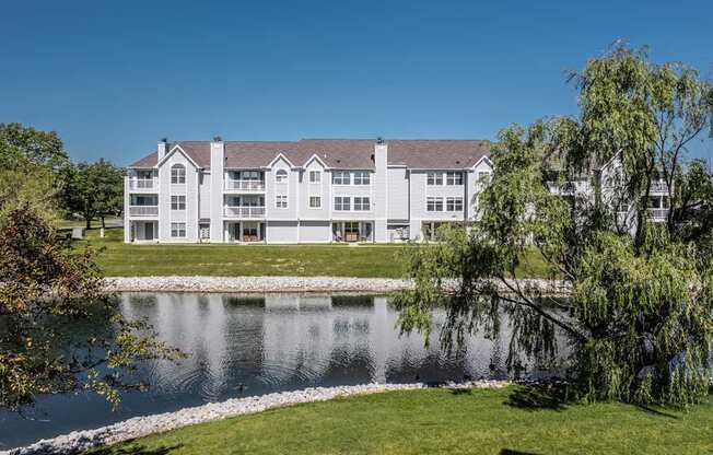 A large white building with a grey roof is situated next to a body of water.