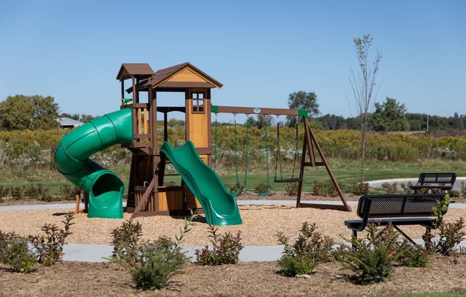 A playground with a green slide and a wooden structure.