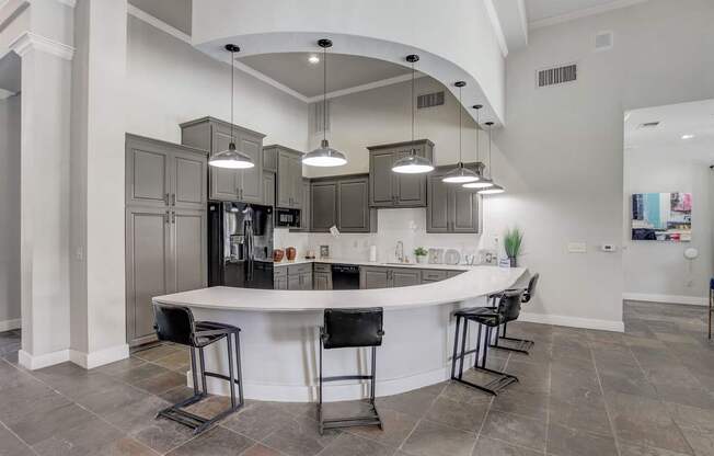A modern kitchen with a curved island and bar stools.