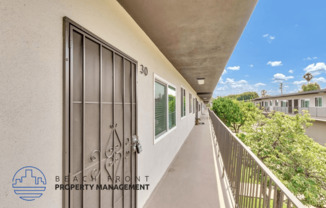 a long balcony with a metal gate and a building with trees