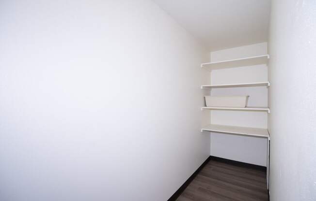 a room with white walls and shelves and a wooden floor. Fargo, ND Country Club Apartments