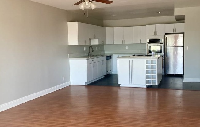 A kitchen with white cabinets and a wooden floor.