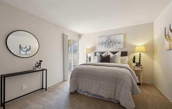 A bedroom with a bed, a mirror, and a painting on the wall.