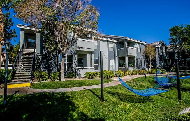 a hammock sits in the grass in front of an apartment building