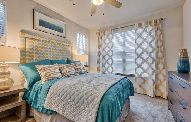 bedroom with the bed and dresser and night stand and window and ceiling fan at Parc at Bentonville Apartments in Bentonville, AR