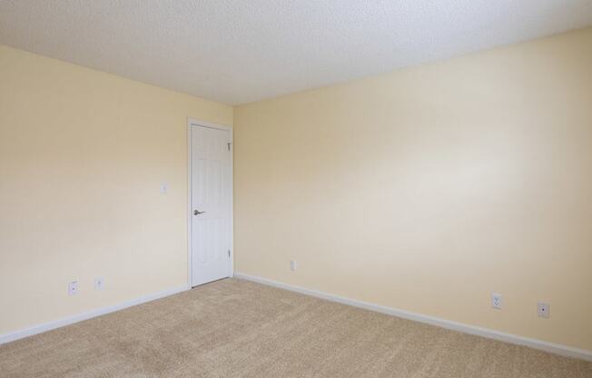 A room with a white door and beige walls.