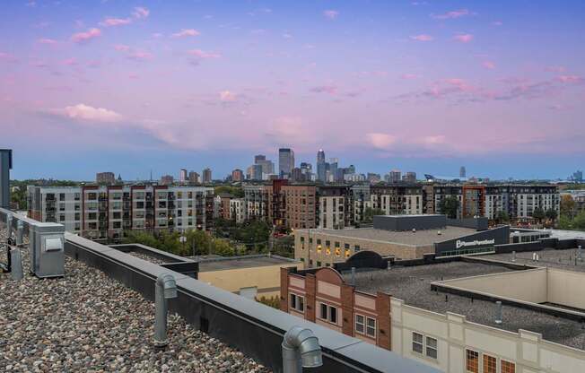 A train track with a train on it in the foreground with a city skyline in the background.