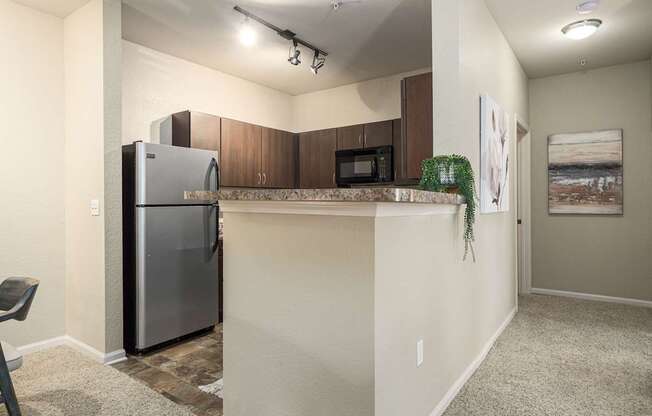 A kitchen area with a refrigerator, microwave, and a countertop.
