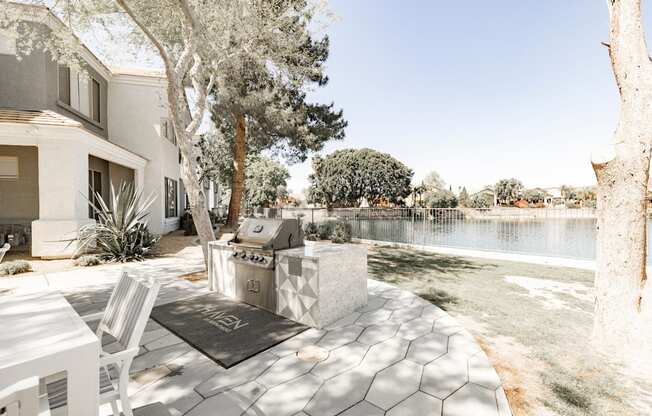 A patio with a white chair and a table is surrounded by trees.