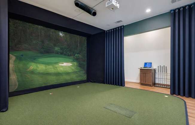 A room with a golf simulator and a green carpet.