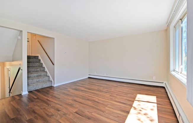 an empty living room with wood flooring and a staircase