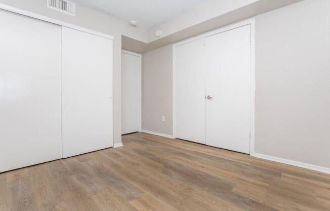 A room with two white doors and a wooden floor.